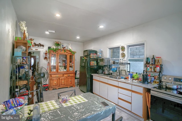 kitchen with stainless steel electric range oven, light countertops, freestanding refrigerator, white cabinets, and a sink