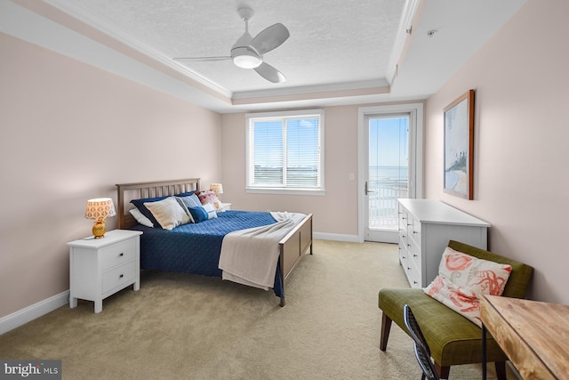 bedroom with a textured ceiling, ceiling fan, light carpet, and a tray ceiling