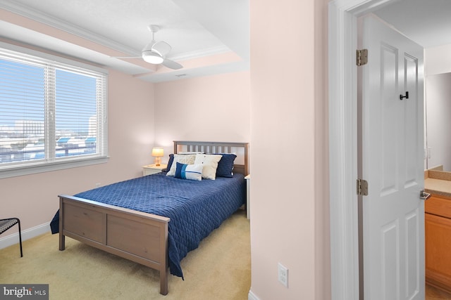 carpeted bedroom with a tray ceiling, crown molding, and ceiling fan