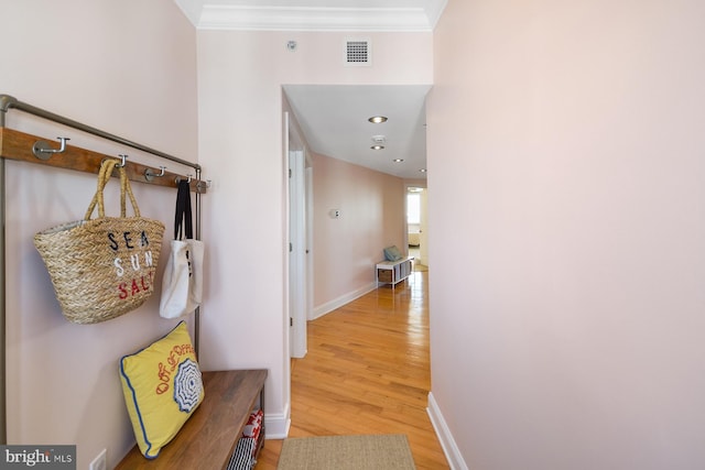 corridor with light wood-type flooring and crown molding