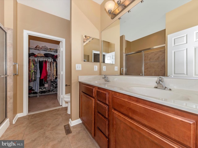 bathroom with tile patterned flooring, a shower with door, vanity, and toilet