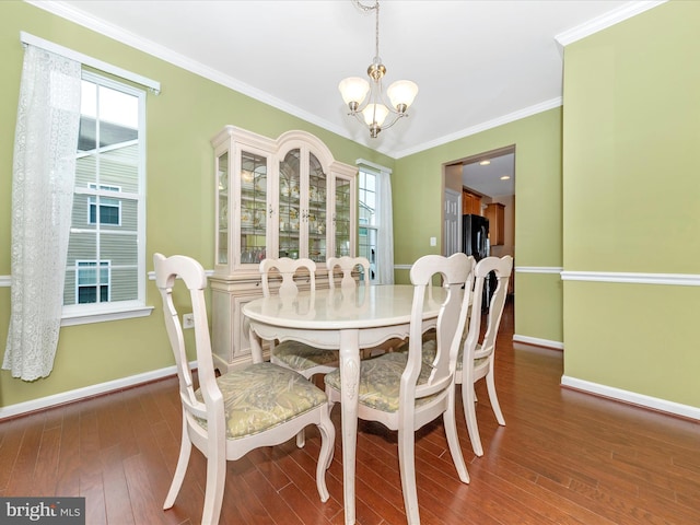 dining room with ornamental molding, a notable chandelier, plenty of natural light, and dark hardwood / wood-style floors