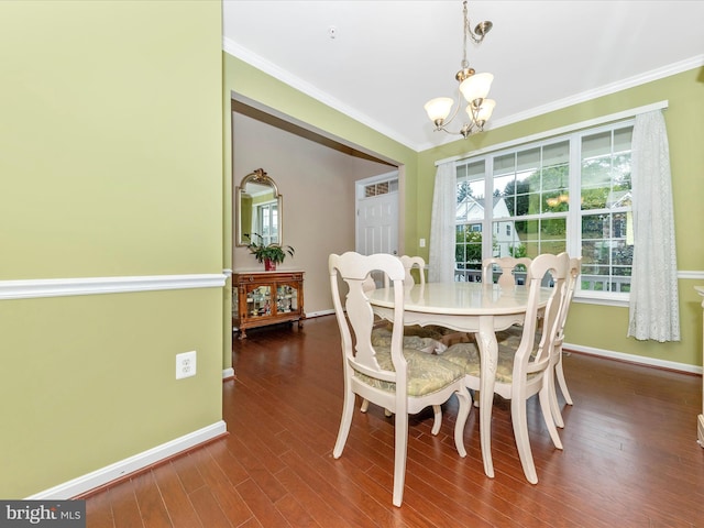 dining area with an inviting chandelier, crown molding, and dark wood-type flooring