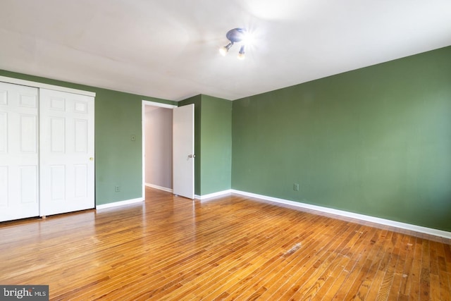 unfurnished bedroom featuring a closet, baseboards, and wood finished floors