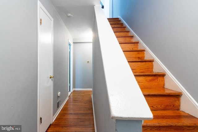 staircase featuring baseboards and wood finished floors