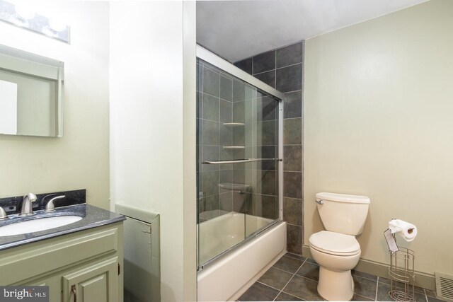 full bathroom with shower / bath combination with glass door, tile patterned flooring, toilet, and vanity