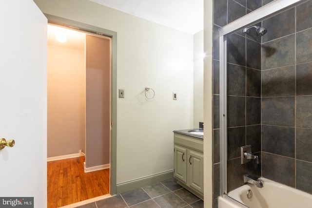 bathroom with hardwood / wood-style floors, tiled shower / bath combo, and vanity