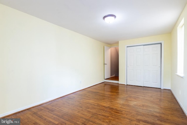 unfurnished bedroom featuring a closet, dark wood-style flooring, and baseboards