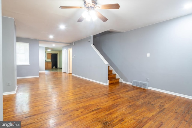 unfurnished living room with baseboards, stairs, visible vents, and wood finished floors