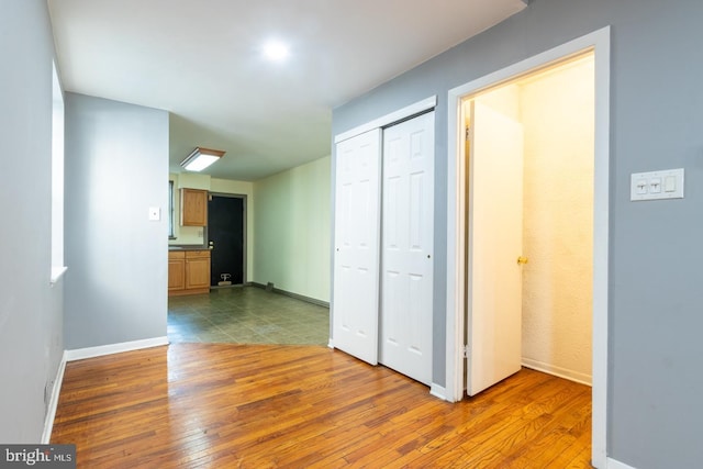 corridor featuring light wood-type flooring and baseboards