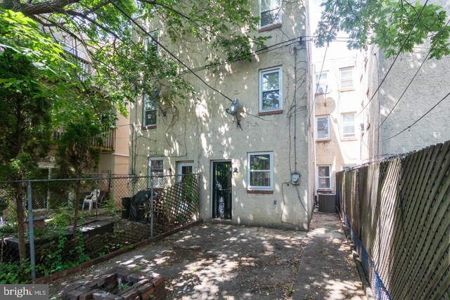 back of property with central AC unit and a patio