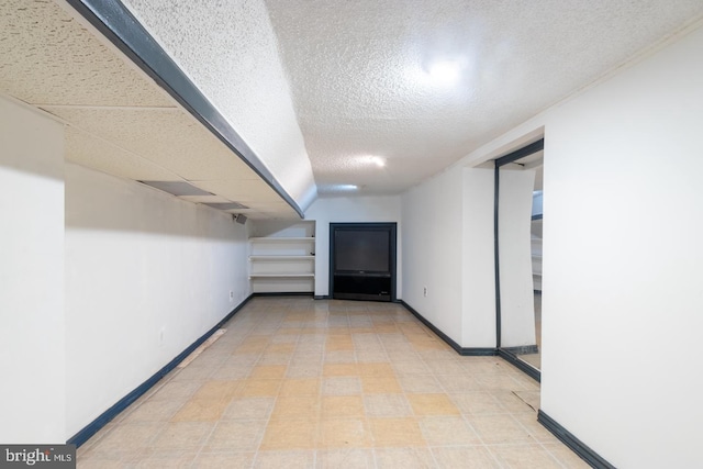 hallway featuring a textured ceiling and baseboards