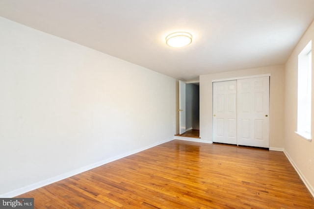 unfurnished bedroom featuring a closet, light wood-type flooring, and baseboards