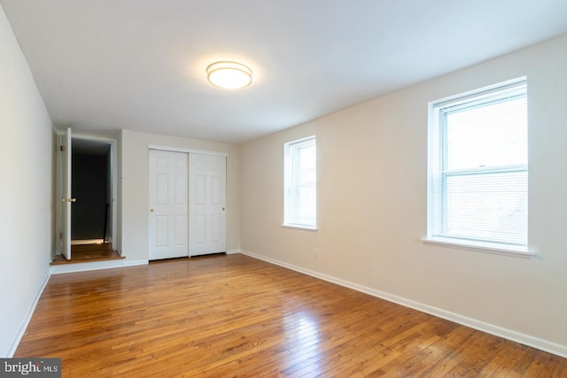 unfurnished bedroom with a closet, baseboards, and light wood finished floors