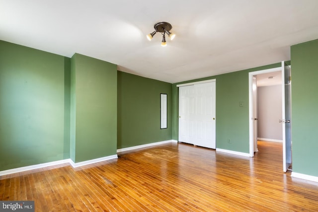 unfurnished bedroom featuring a closet, wood finished floors, and baseboards