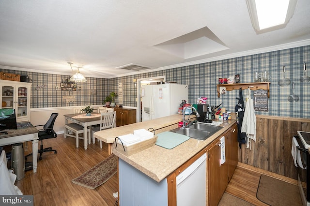 kitchen featuring sink, crown molding, wood-type flooring, kitchen peninsula, and white appliances