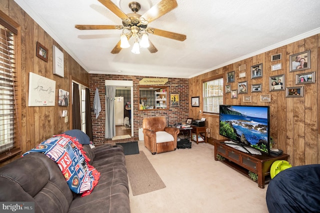 carpeted living room with ceiling fan, brick wall, wood walls, ornamental molding, and a textured ceiling