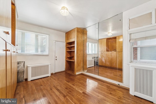 unfurnished bedroom with wood-type flooring and radiator heating unit