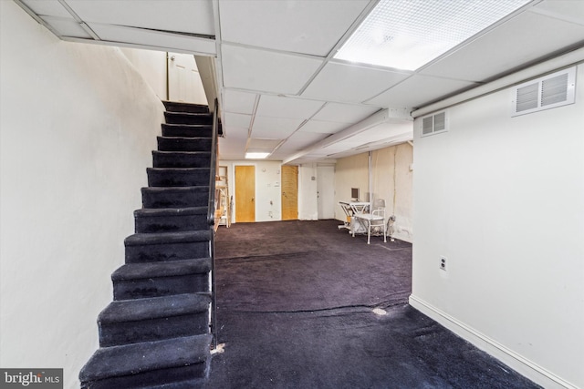 basement with a paneled ceiling and carpet