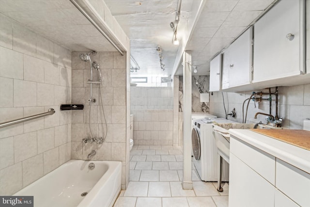 bathroom featuring tile patterned flooring, independent washer and dryer, tile walls, and tiled shower / bath