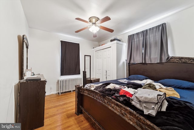 bedroom featuring a closet, ceiling fan, radiator heating unit, and light hardwood / wood-style floors