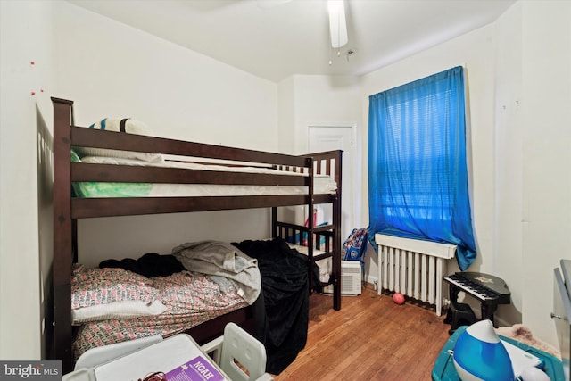 bedroom with hardwood / wood-style floors, radiator, and ceiling fan