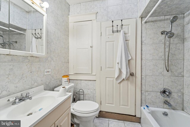 full bathroom with vanity, toilet, tiled shower / bath, and tile walls