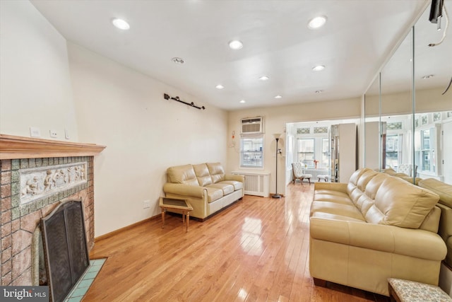 living room featuring a fireplace, light wood-type flooring, an AC wall unit, and radiator