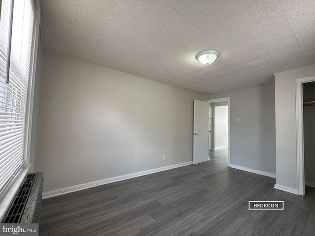 interior space featuring dark wood-type flooring, visible vents, and baseboards