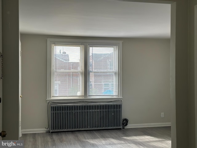 spare room with light wood finished floors, radiator heating unit, and baseboards