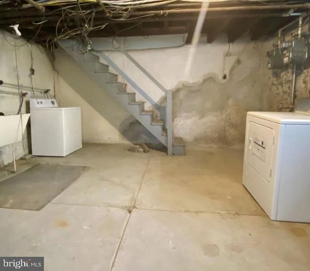 unfinished basement featuring washing machine and dryer, stairway, and a sink