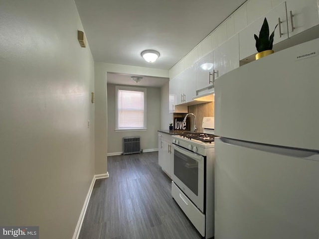 kitchen with dark countertops, radiator, white cabinets, white appliances, and baseboards