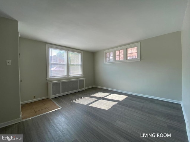 spare room with radiator heating unit, dark wood finished floors, and baseboards