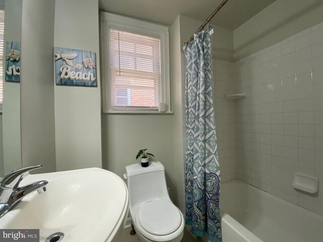 full bathroom with sink, shower / tub combo with curtain, and toilet