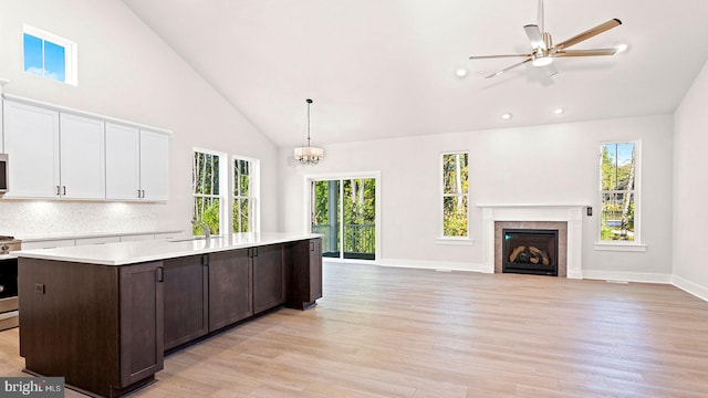 kitchen with a wealth of natural light, high vaulted ceiling, pendant lighting, and light wood-type flooring