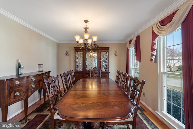 dining area featuring baseboards, ornamental molding, dark wood finished floors, and a notable chandelier