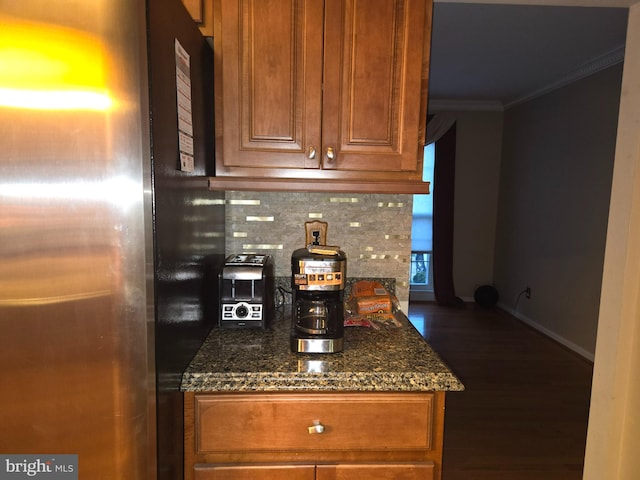 interior space featuring dark wood finished floors, crown molding, backsplash, freestanding refrigerator, and baseboards