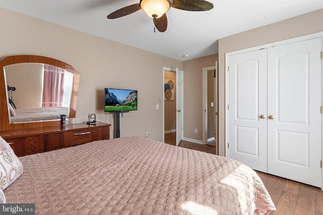 bedroom with dark wood-style floors, a closet, a ceiling fan, and baseboards