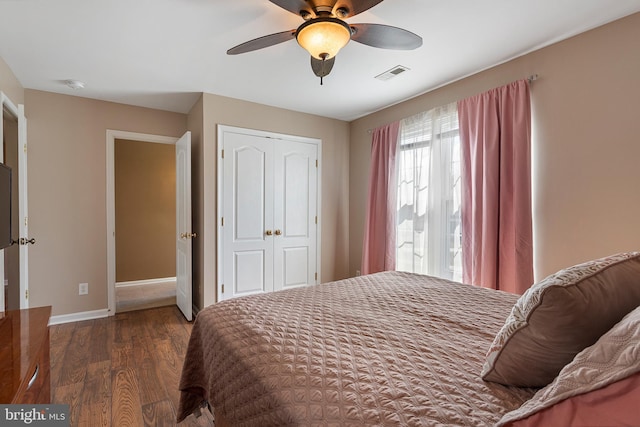 bedroom featuring a closet, visible vents, dark wood-type flooring, a ceiling fan, and baseboards