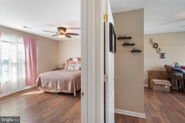 bedroom with dark wood-style floors, ceiling fan, visible vents, and baseboards