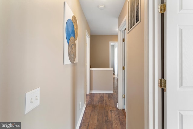 hallway with baseboards, visible vents, and dark wood finished floors