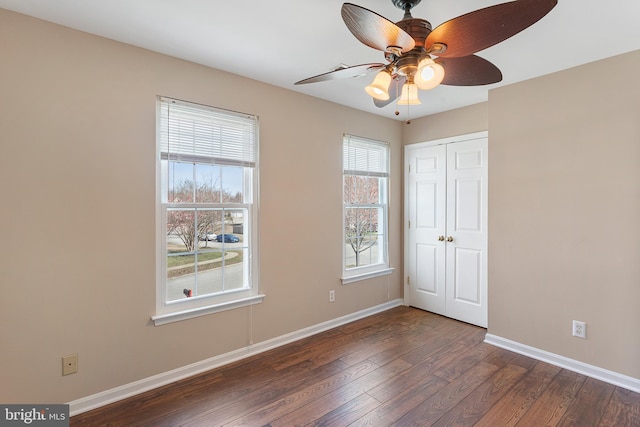 unfurnished bedroom with dark wood-style floors, ceiling fan, baseboards, and a closet