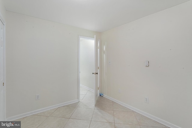 spare room featuring baseboards and light tile patterned floors