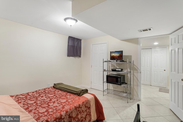 bedroom with light tile patterned flooring, visible vents, and baseboards