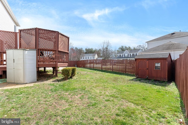 view of yard with a storage shed, a deck, an outbuilding, and a fenced backyard