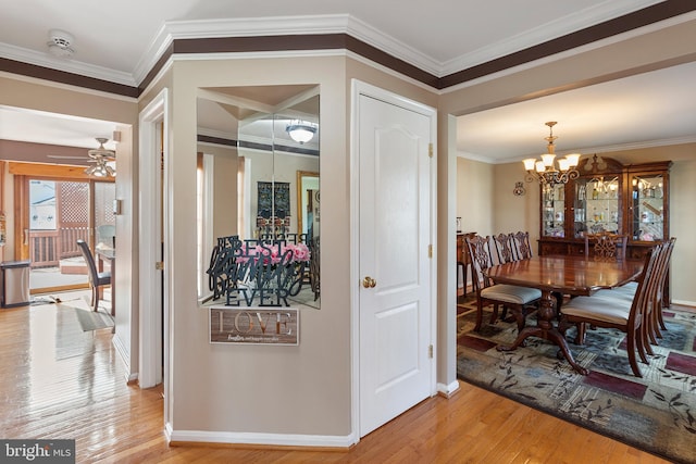 dining area with ceiling fan with notable chandelier, crown molding, baseboards, and wood finished floors