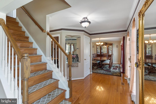 entrance foyer featuring light wood-style floors, visible vents, crown molding, and an inviting chandelier