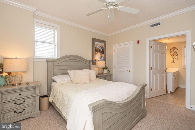 carpeted bedroom featuring ceiling fan, ornamental molding, a closet, and ensuite bathroom