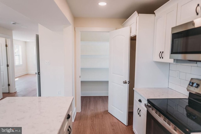 kitchen with appliances with stainless steel finishes, decorative backsplash, light hardwood / wood-style floors, and white cabinets