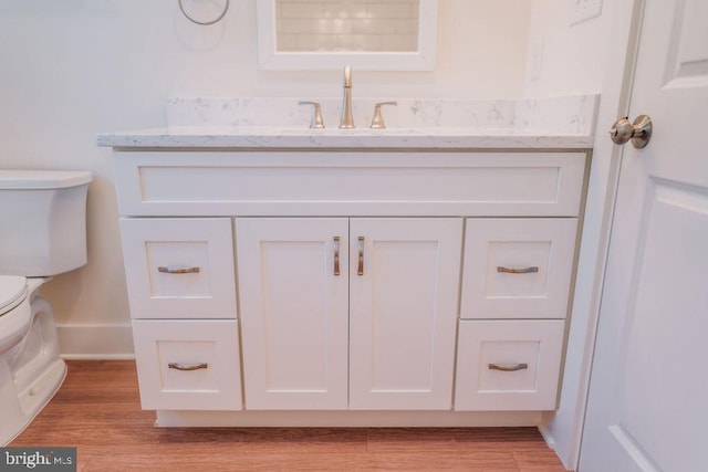 bathroom with wood-type flooring, vanity, and toilet